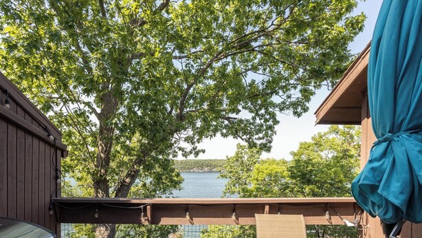 Une terrasse en bois avec un barbecue, une chaise et une vue sur un lac.