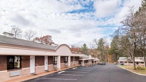 A row of motel rooms with a parking lot in front. - Kingston Motel (Kingston)