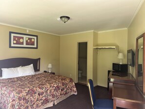 A hotel room with a bed, a desk, a chair, a television, and a door leading to a bathroom. - Kingston Motel (Kingston)