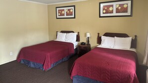 A hotel room with two beds, each with a red bedspread and white pillows. There are framed pictures on the wall, a bedside table with a lamp, and a ceiling light. - Kingston Motel (Kingston)