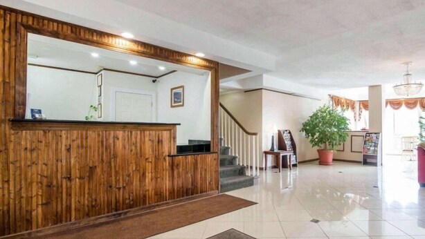 A reception area with a wooden reception desk, a staircase, and a potted plant. - Kingston Motel (Kingston)
