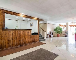 A reception area with a wooden reception desk, a staircase, and a potted plant. - Kingston Motel (Kingston)