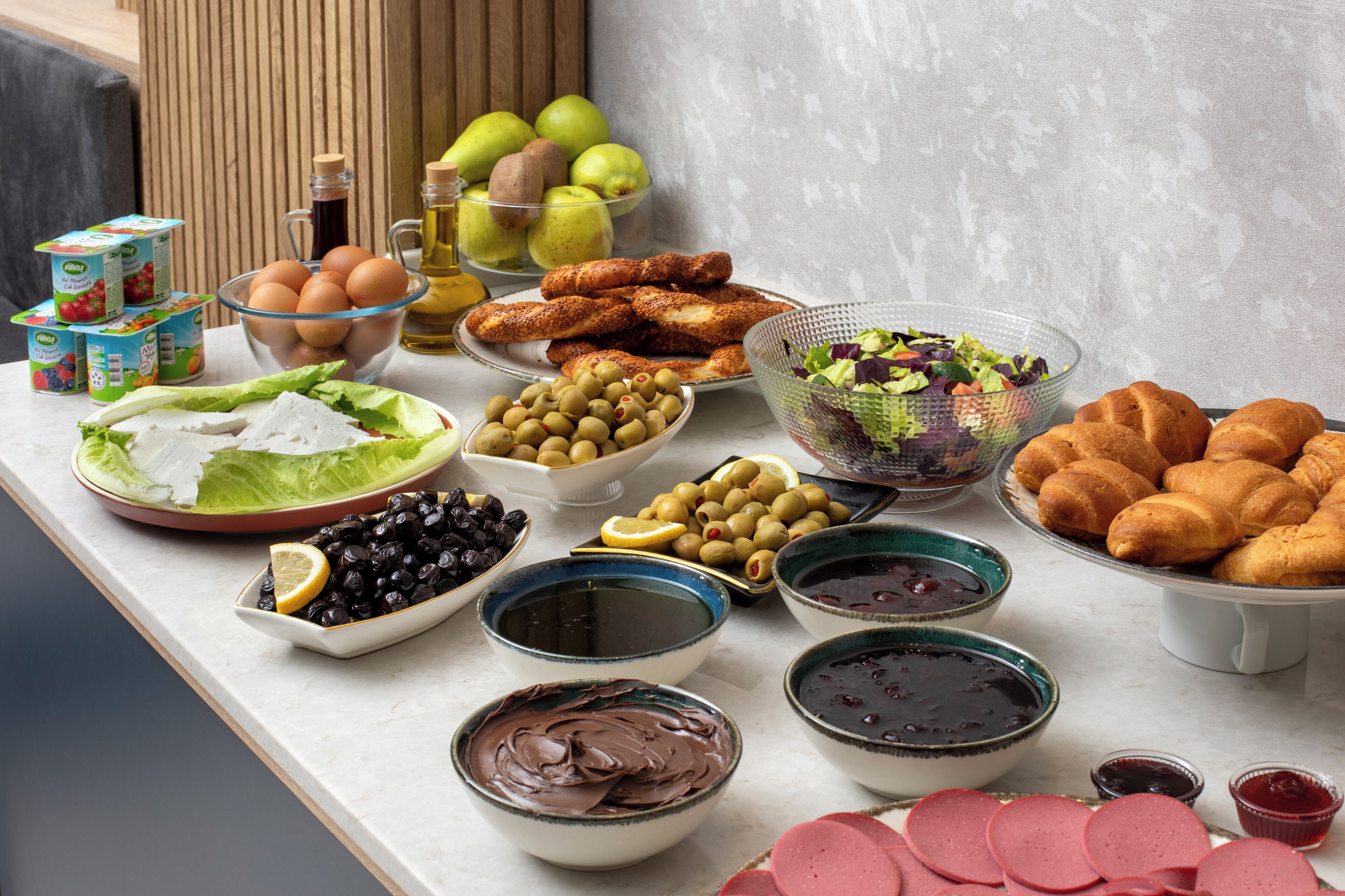 A table with various food items including bread, olives, eggs, and a salad.