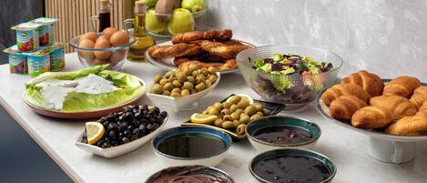 A table with various food items including bread, olives, eggs, and a salad.