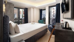 A modern hotel room with a bed, a desk, a chair, a TV, and large windows. - Lenus Hagia Sophia Hotel (Istanbul)