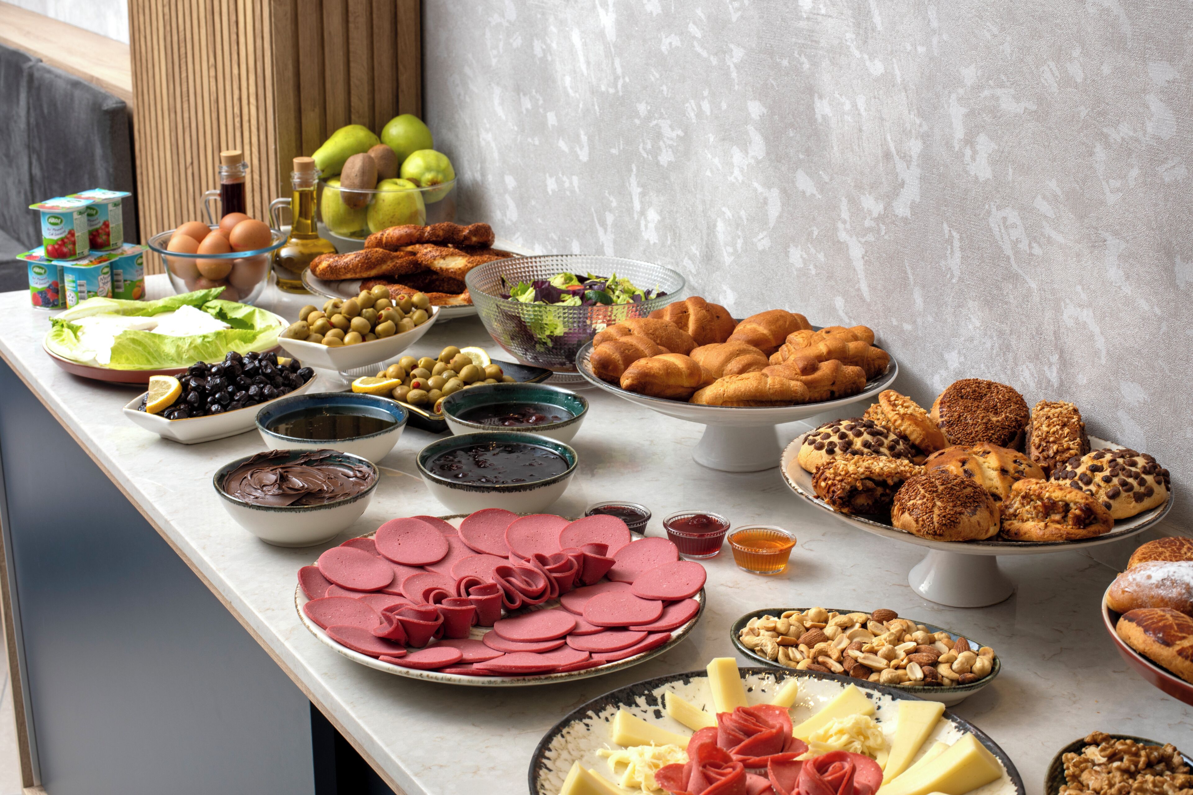 A buffet table with various food items including meats, cheeses, fruits, and pastries.