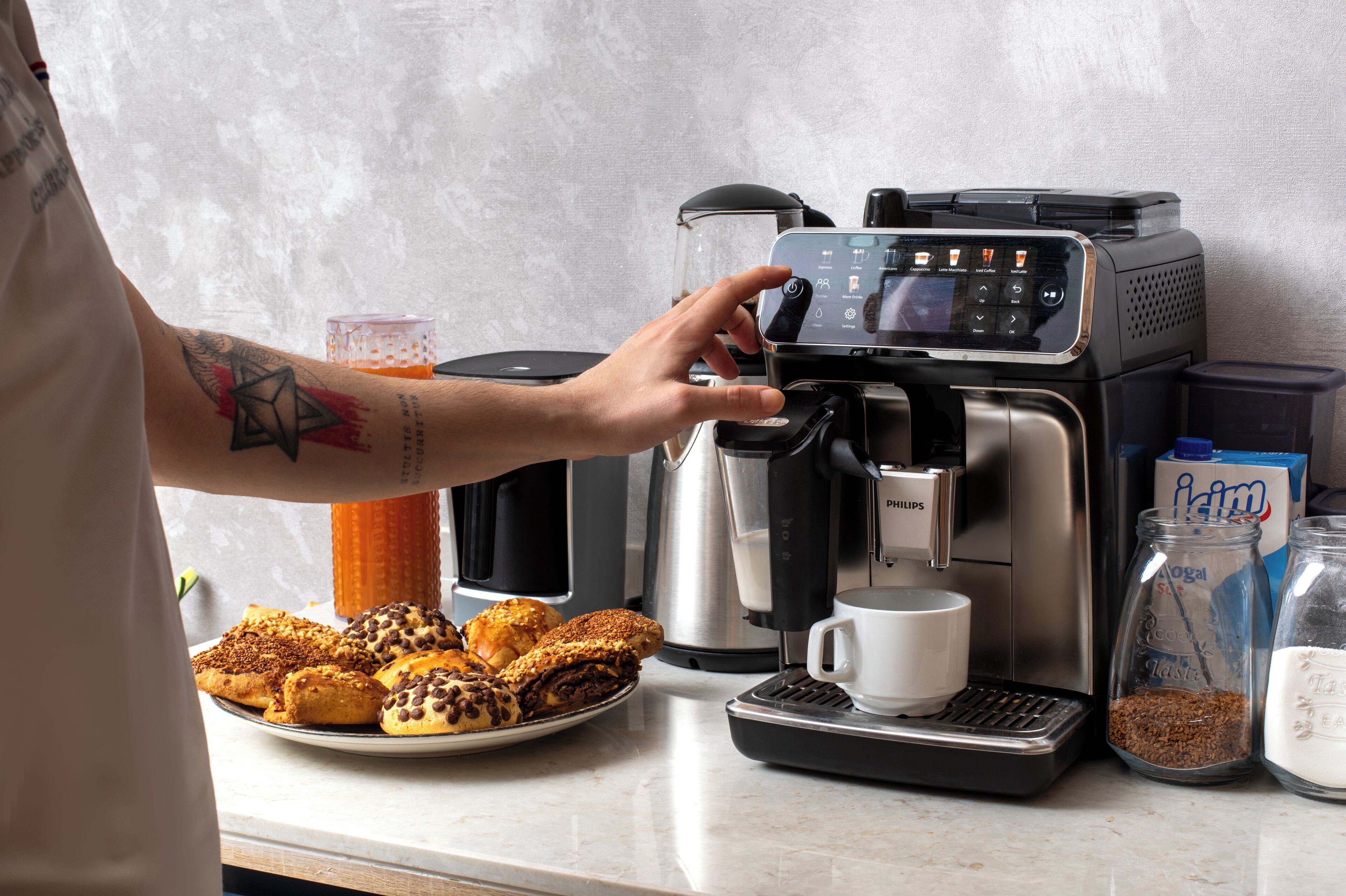 Máquina de café com interface digital, jarra de café, vaporizador de leite e moedor de grãos.