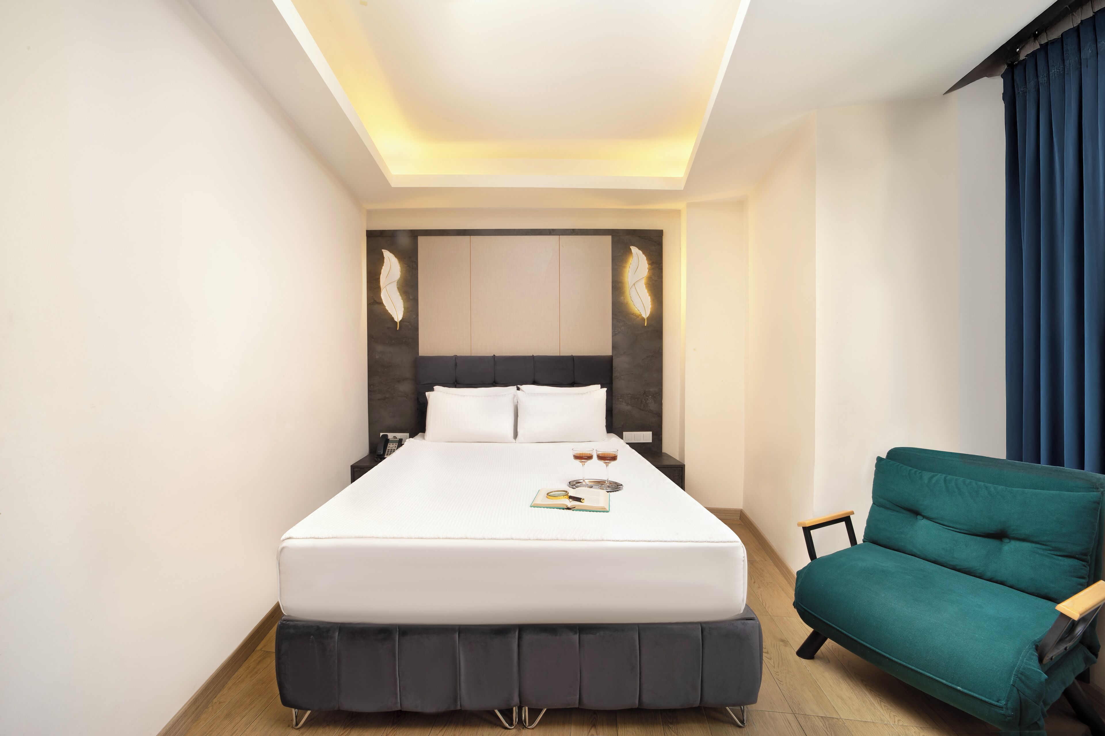 A modern hotel room with a large bed, a small armchair, and a nightstand.