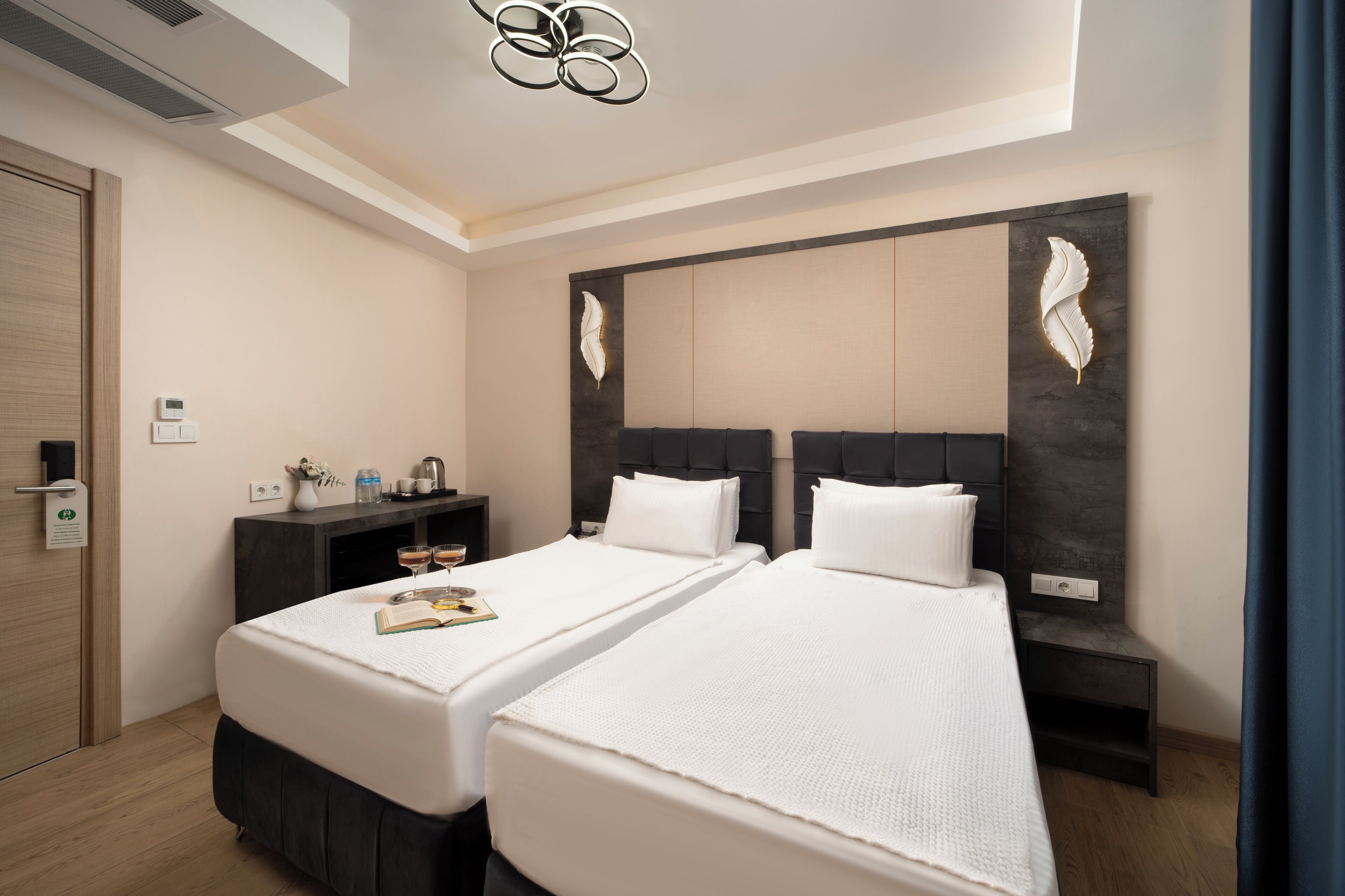A hotel room with two beds, a desk, a chair, and a small table.