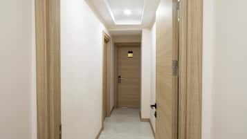 A narrow hallway with wooden doors and a ceiling light.