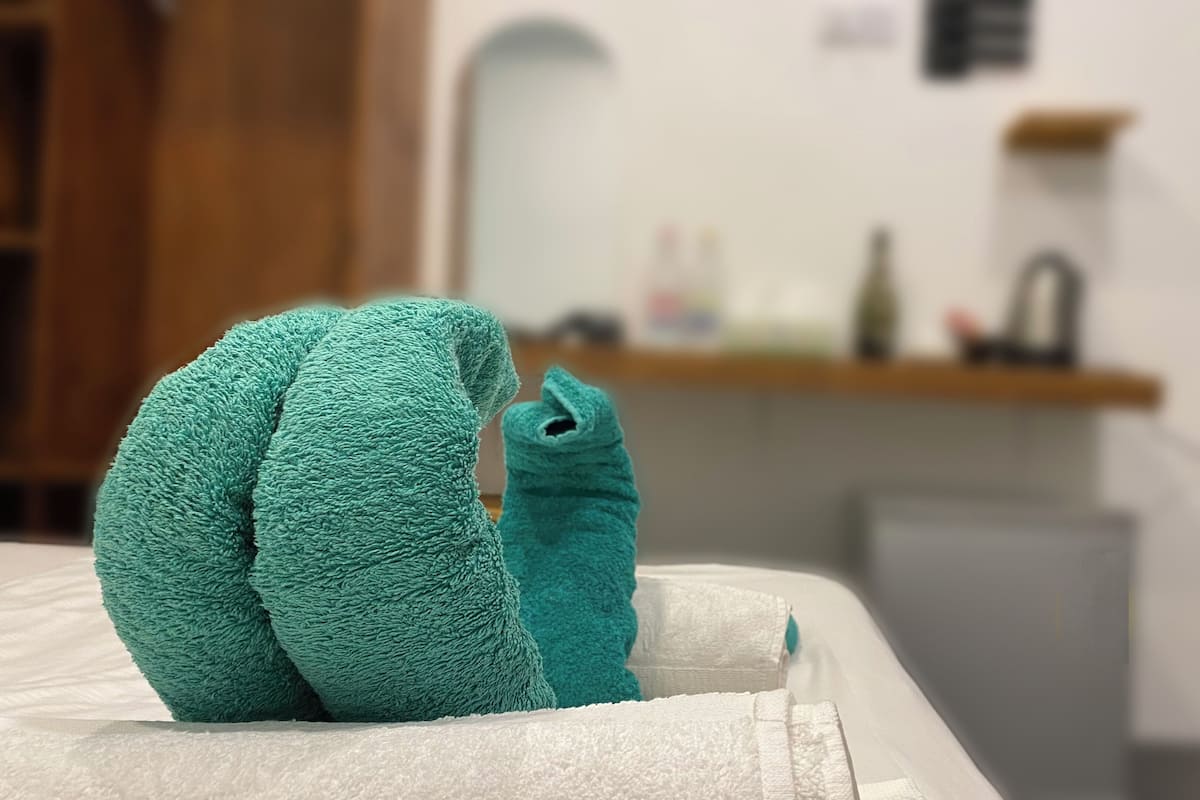 A bed with a green towel and a white towel.