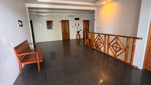 Un pasillo espacioso con un banco de madera, una escalera con barandilla de madera y un suelo pulido oscuro.