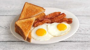 Un plato con tostadas, tocino y dos huevos fritos.