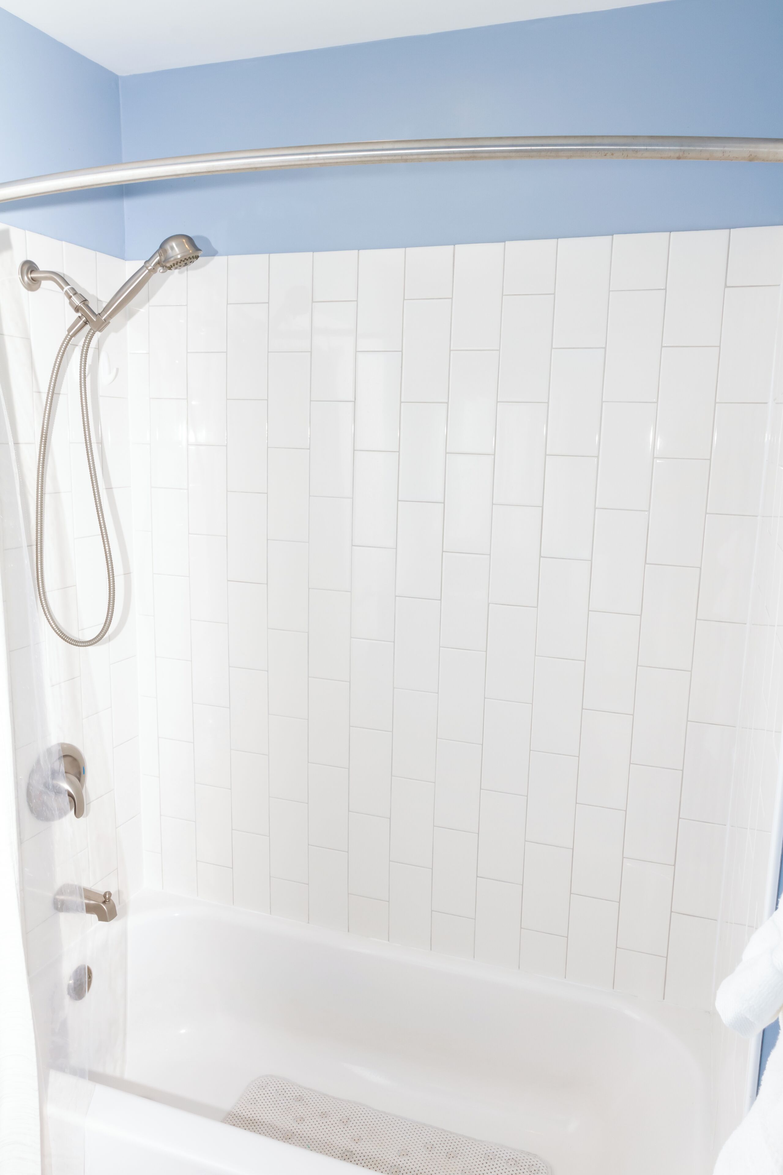 A bathroom with a white bathtub, a shower with a handheld showerhead, and a clear glass shower enclosure.