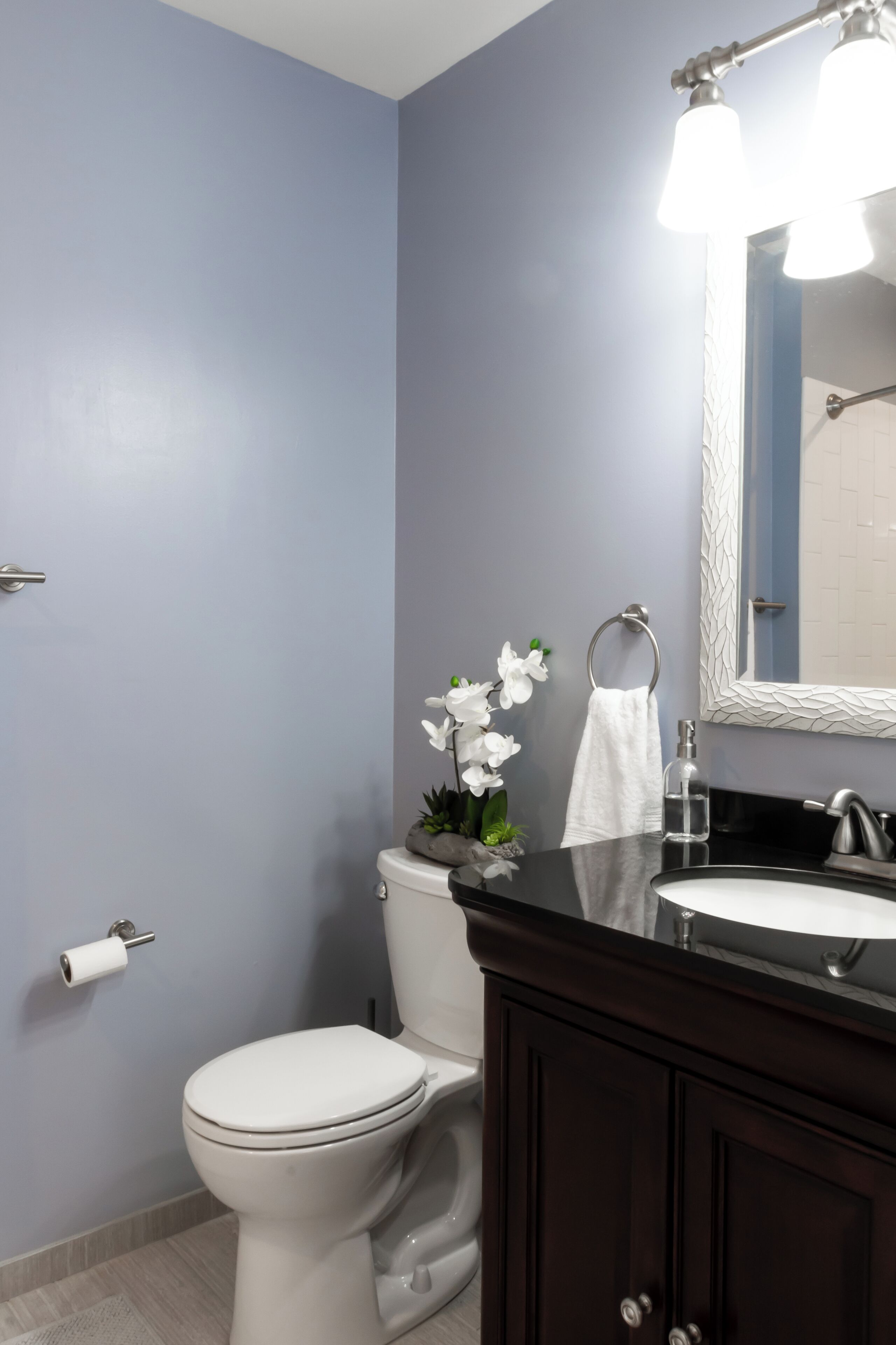 A bathroom with a toilet, sink, and mirror.