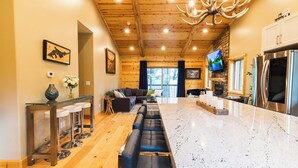 A spacious kitchen with a large island, wooden ceiling, and a stone fireplace. - SNOW BUNNY - Game Room - Hot Tub - Fire Pit (Big Bear Lake)