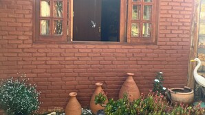 Un edificio de ladrillo con un gran ventanal y una puerta. Cerca de la entrada hay macetas de terracota y una escultura de un pájaro.