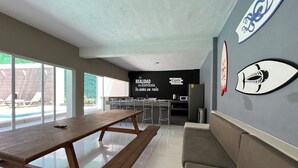 Un espacio interior moderno con un banco de madera, una zona de bar y una pared decorada con motivos de peces.