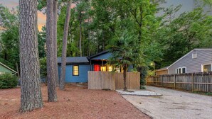 A cabin with a blue exterior, surrounded by tall trees and a wooden fence. - Outdoorsy ~ Fresh Spring Vibes ~ Sauna & Cold Plunge ~ 10min Downtown (Raleigh)