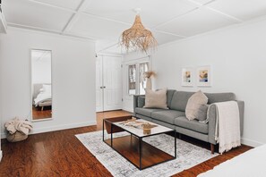 Uma sala de estar moderna com um sofá cinzento, uma mesa de centro e um candeeiro suspenso.