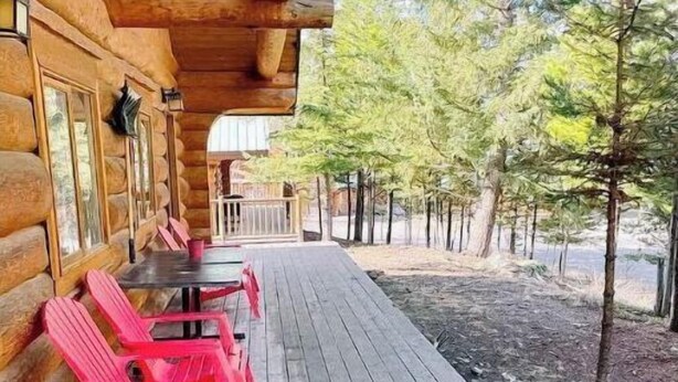 A wooden deck with a covered seating area, surrounded by trees.
