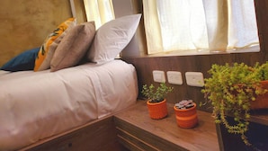 A cozy bedroom with a bed, pillows, a wooden bench, and potted plants. - Sun Backpackers (Quito)