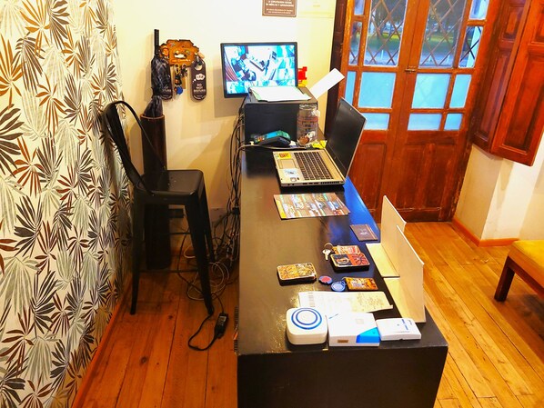 A room with a wooden desk, two laptops, a computer monitor, and various items like keys and a USB drive.