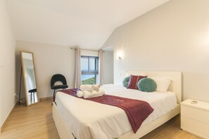 Une chambre à coucher avec un lit, une table de chevet, une chaise, une fenêtre avec des rideaux et un miroir.