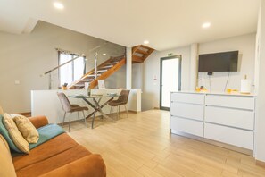 Une cuisine moderne avec un coin repas, un escalier en bois et un téléviseur à écran plat fixé au mur.