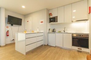 Eine moderne Küche mit weißen Schränken, einer eingebauten Mikrowelle, einem Herd und einem an der Wand montierten Fernseher.
