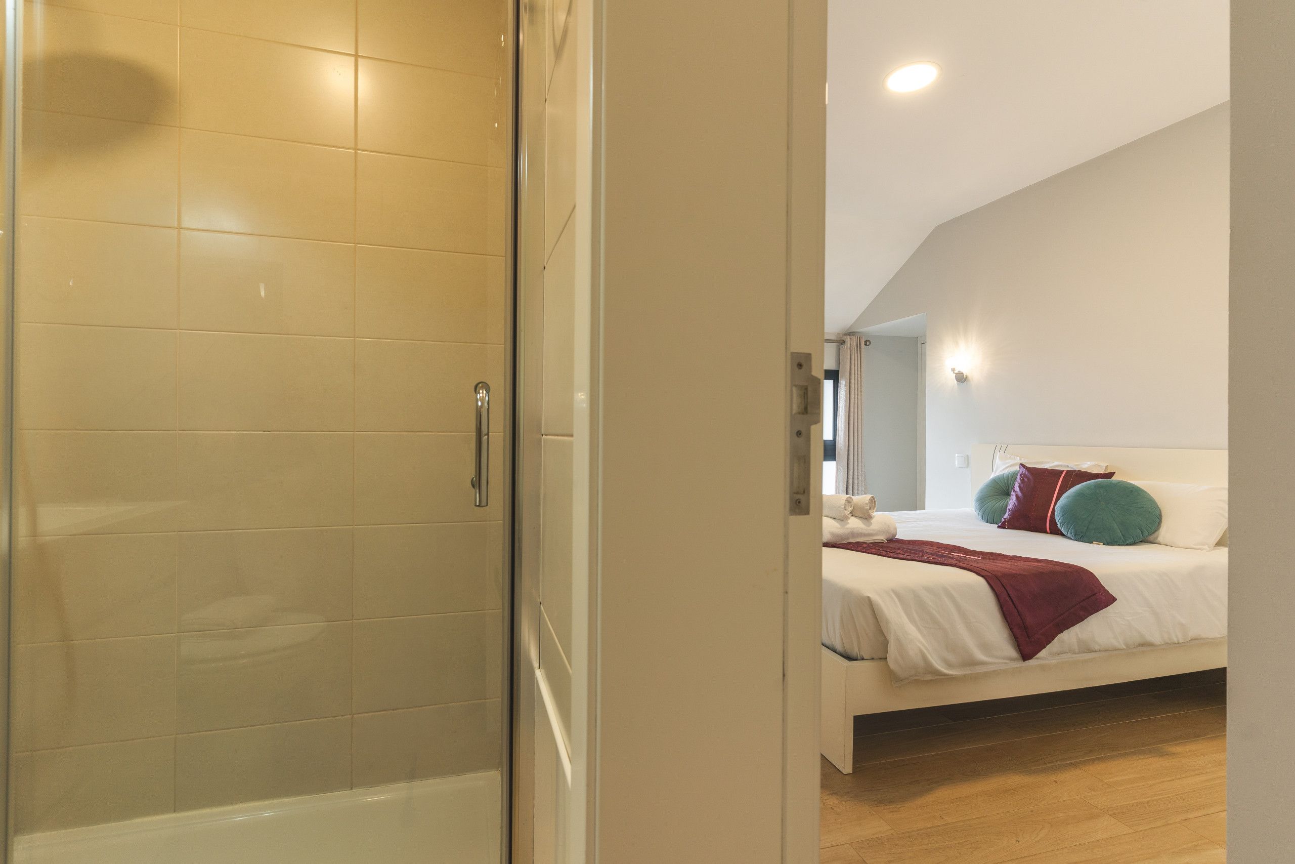 Ein Hotelzimmer mit Dusche, einem Bett mit Kissen und einem Kopfteil.