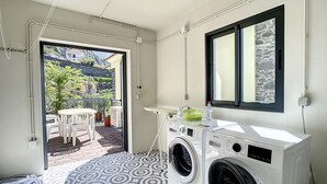 Ein Waschbereich mit Waschmaschine, einem kleinen Tisch und einem Fenster.