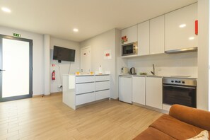 A modern kitchen with white cabinetry, a microwave, an oven, and a coffee maker.