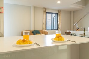 A modern kitchen with a white countertop, two plates of croissants, and two glasses of orange juice. - My School I by Atlantic Holiday (Ponta Delgada)