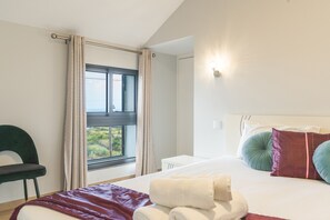 A hotel room with a bed, a chair, a window with curtains, and a wall-mounted light fixture. - My School I by Atlantic Holiday (Ponta Delgada)
