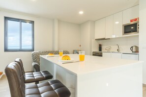 A modern kitchen with a central island, white cabinetry, and a window providing natural light.
