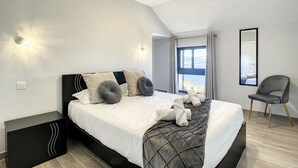 Ein modernes Schlafzimmer mit einem Bett, einem Nachttisch und einem Sessel.