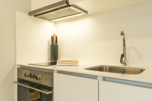 A kitchen with a stainless steel sink, a built-in oven, and a range hood.