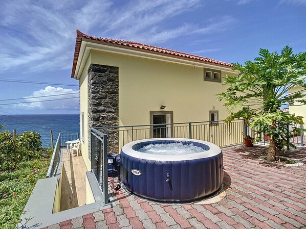 A spa area with a hot tub, a stone wall, and a view of the ocean.