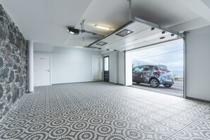 A spacious room with patterned flooring, a stone wall, and a large sliding door leading outside.