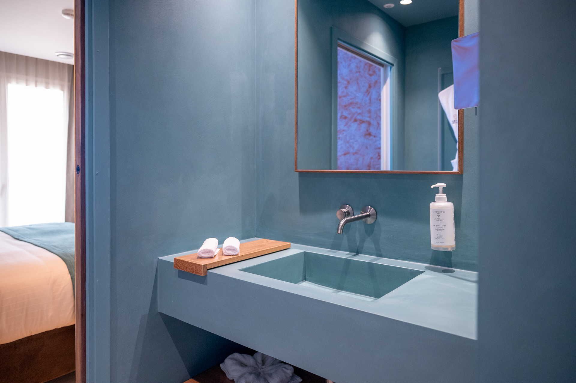 A modern bathroom with a glass sink, wooden vanity, and a mirror.