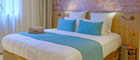A hotel room with a bed, a laptop, a bedside table, and a wall with a textured pattern.