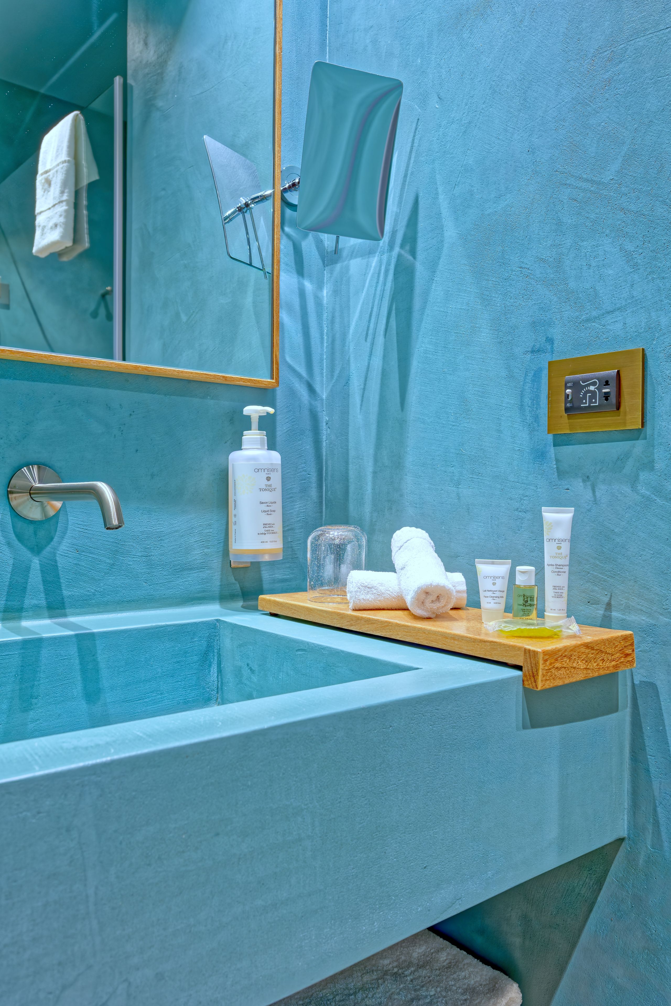 Une salle de bain avec une grande baignoire, un miroir, un porte-serviettes et des articles de toilette disposés sur une étagère en bois.