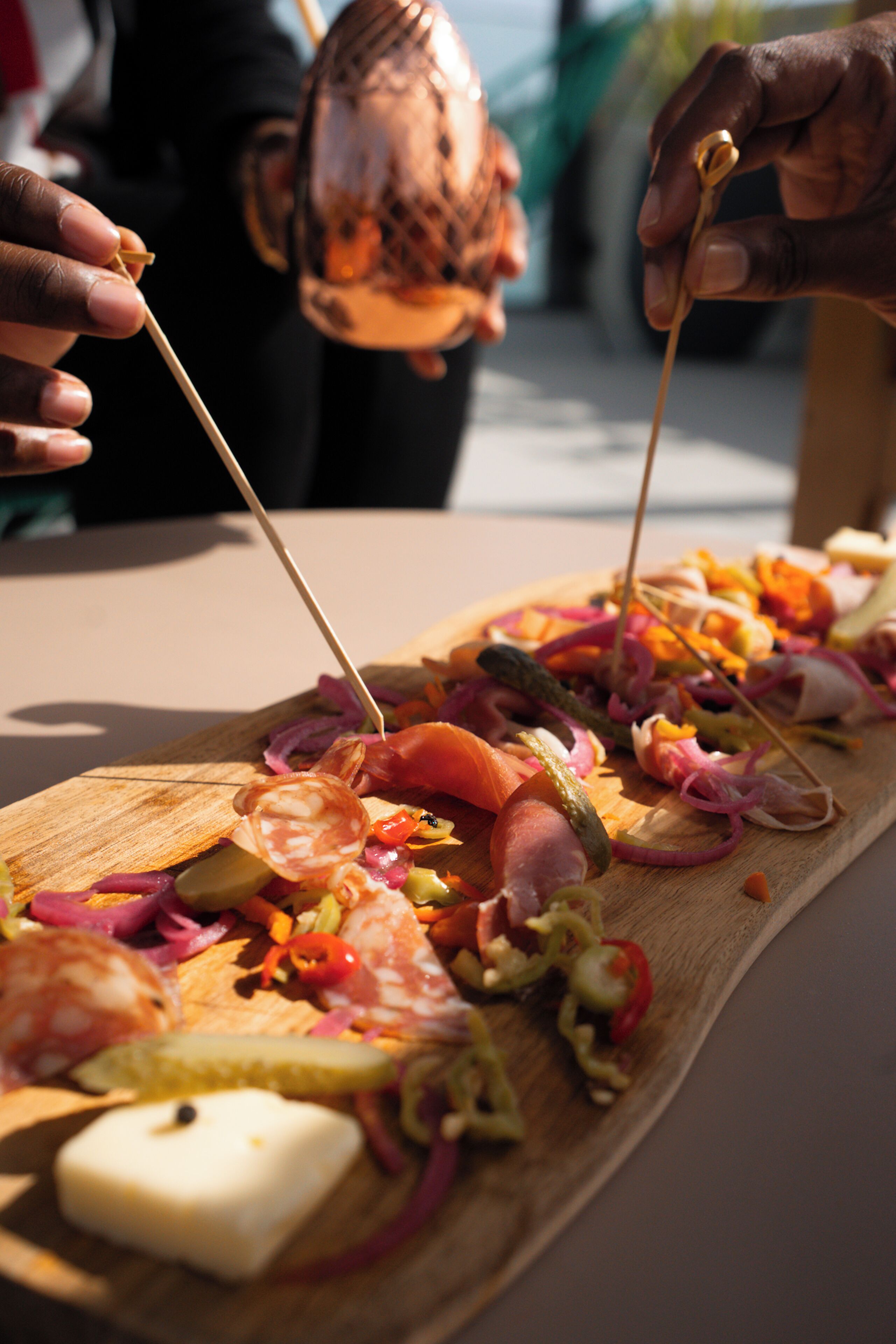 Ein Holzbrett mit verschiedenen Fleisch- und Gemüsesorten, vermutlich eine Wurstplatte.