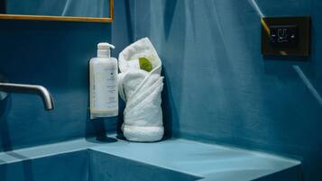 Un baño con un lavabo azul, una botella de jabón y una toalla.