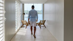 A corridor with a view of the sea, two wicker chairs, and a ceiling lamp. - SABLE BLEU BOUTIQUE HOTEL (Le Marin)