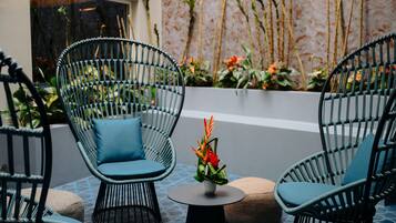 A seating area with wicker chairs and a small table, surrounded by potted plants and a decorative vase.
