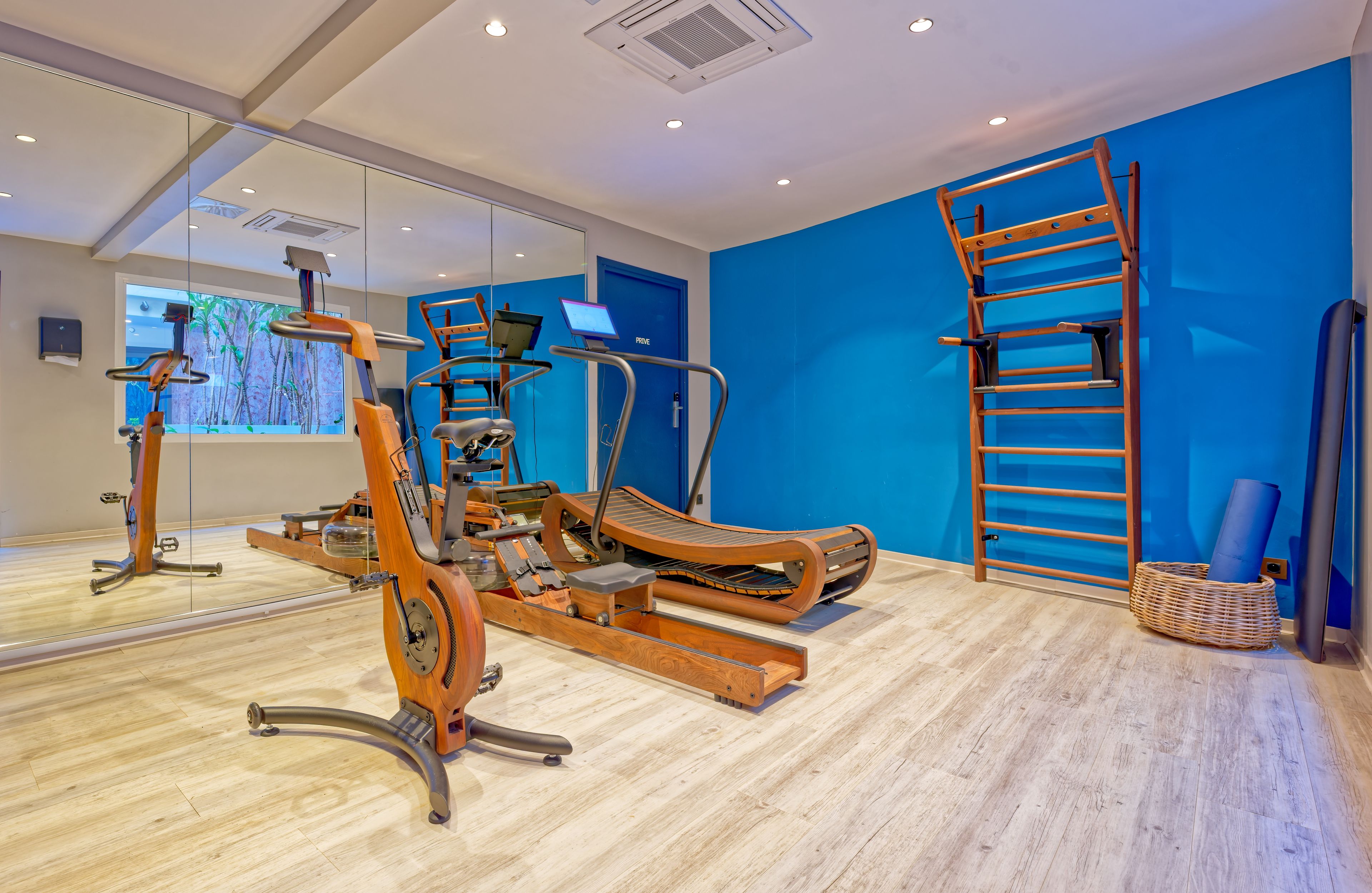 Un gimnasio con equipo de ejercicio, una pared azul y una escalera de madera.