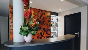 A reception desk with a modern design, featuring a white column, a black door, and a decorative wall with a textured pattern. - SABLE BLEU BOUTIQUE HOTEL (Le Marin)