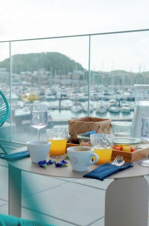 A breakfast table with a view of a marina, a woven bag, and various breakfast items. - SABLE BLEU BOUTIQUE HOTEL (Le Marin)